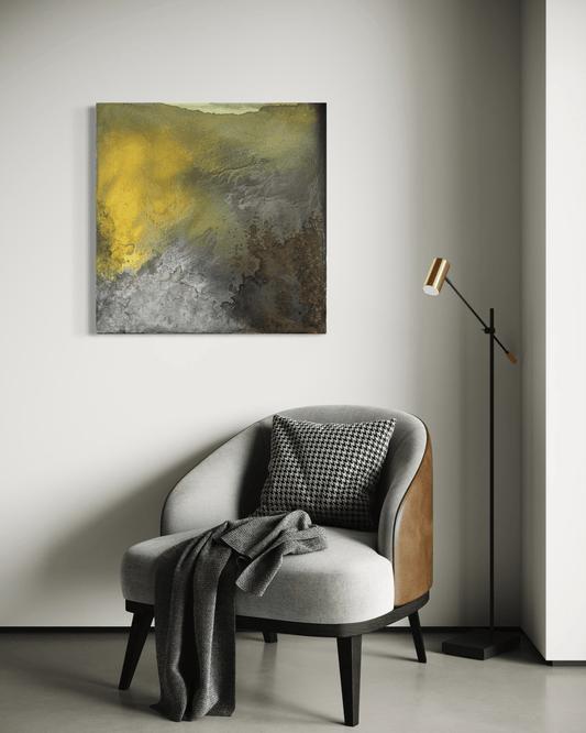Original abstract painting with earth tones of brown, grey, green, gold and silver with layered textures and organic forms displayed above and armchair and floor lamp in modern interior.