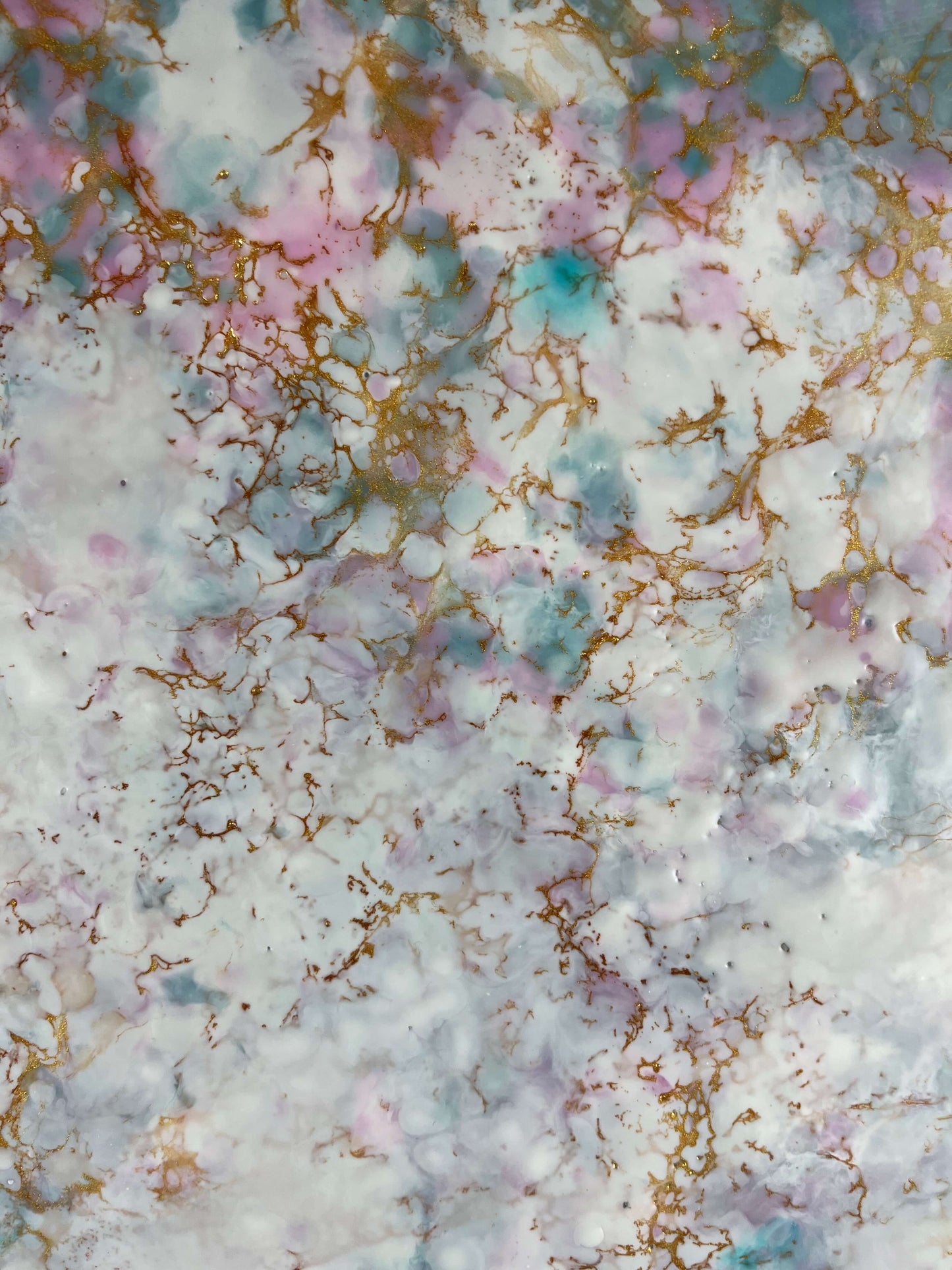 Close up. This abstract painting has a calming feel to it with blue greens, white, pinks and gold. it creates an ethereal feeling with the what looks like a magical cloud floating by.