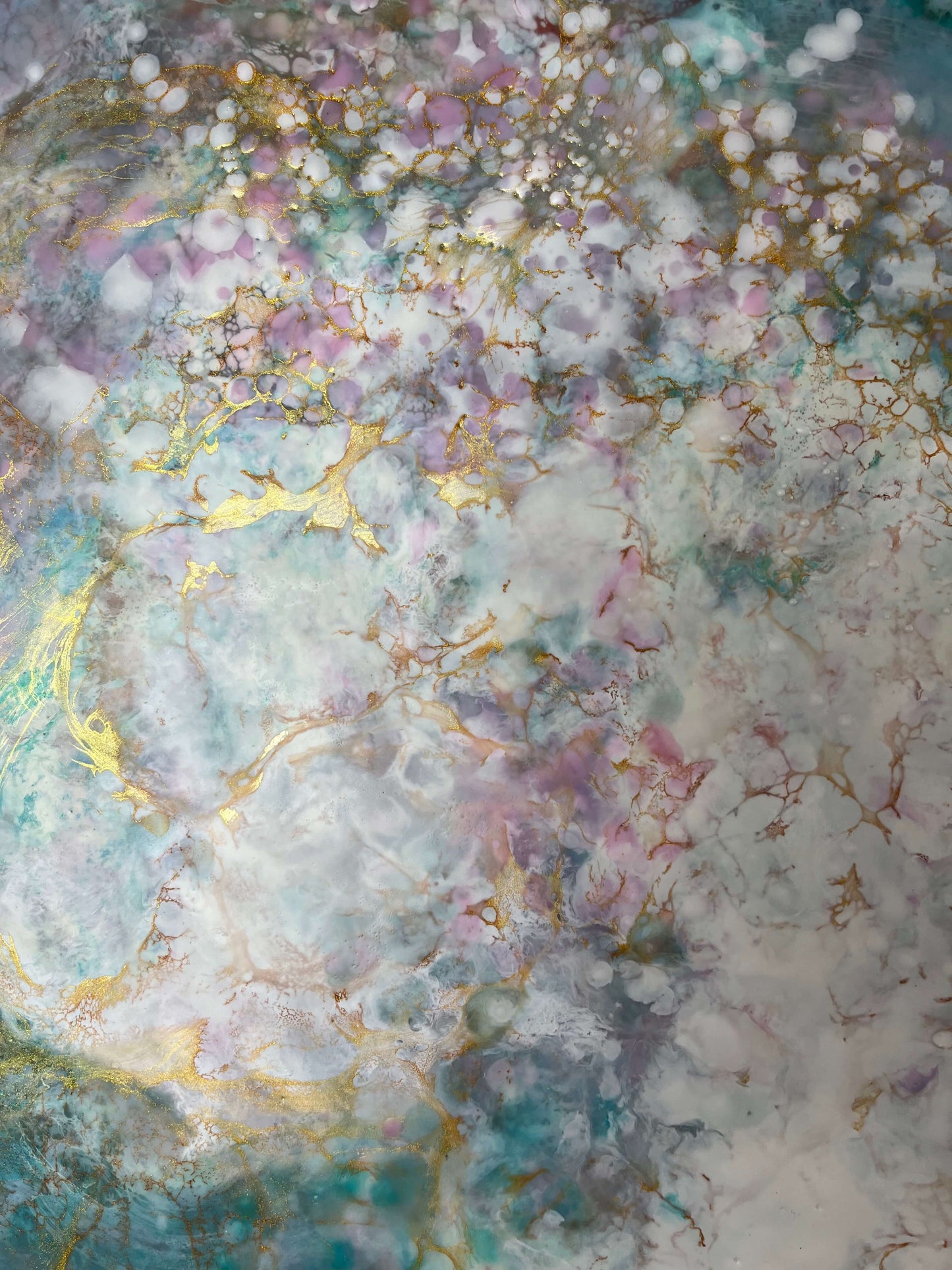 Close up. This abstract painting has a calming feel to it with blue greens, white, pinks and gold. it creates an ethereal feeling with the what looks like a magical cloud floating by.