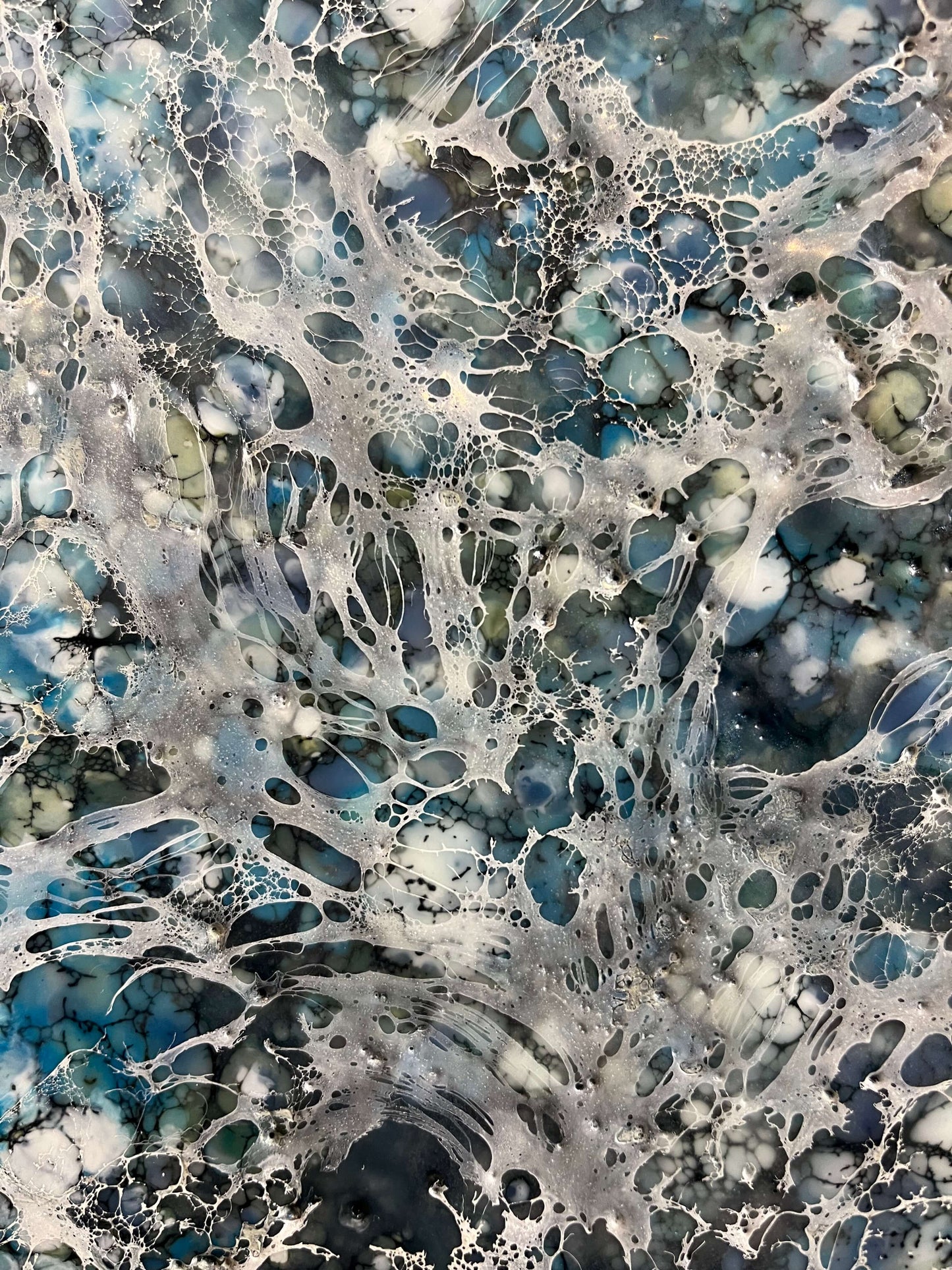 Close up.Encaustic abstract painting in blue and white tones with lots of visual texture and many lace-like swirls. Square panel 40x40inches. It is an abstract painting, and it resembles foaming ocean waters as they hit the rocks.