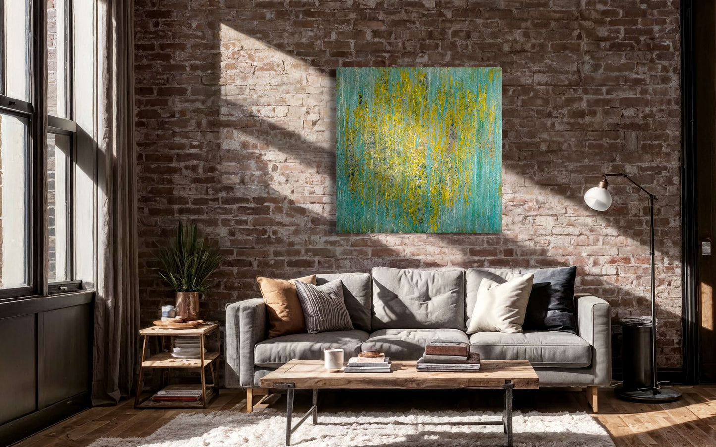 Original abstract encaustic painting in greens, yellows and blues with vertical textured layers displayed on a brick wall above a couch in a modern loft interior