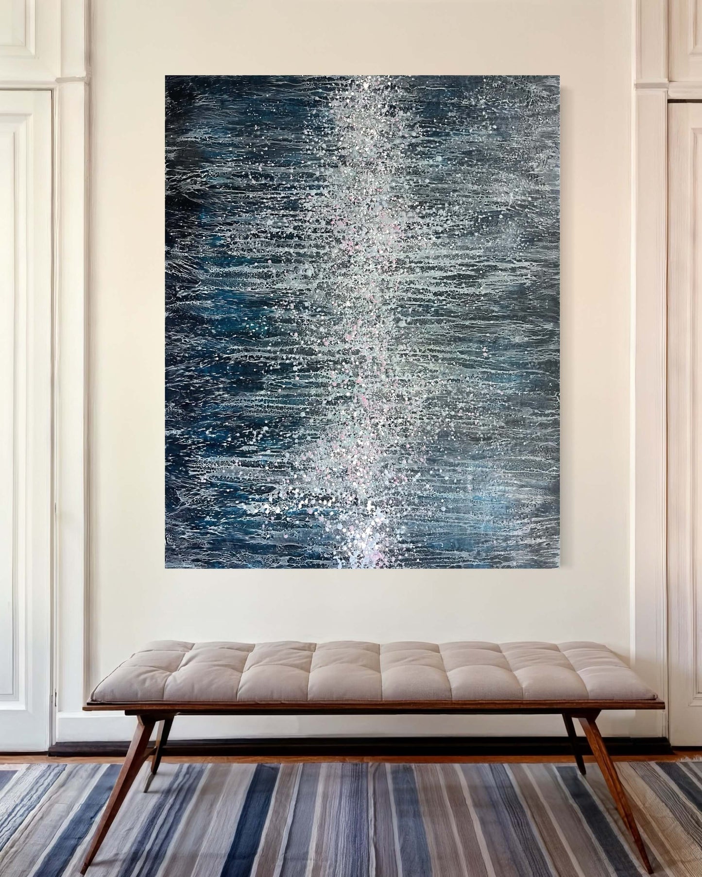 In situ, hung in a vertical position.This 60x48in painting is created in dark, moody blues with many intricate and lace like lines traveling towards the centre of the painting. Down/across the middle of this piece are a cluster of many drips and splatters of wax in pinks, white and light blue colours.