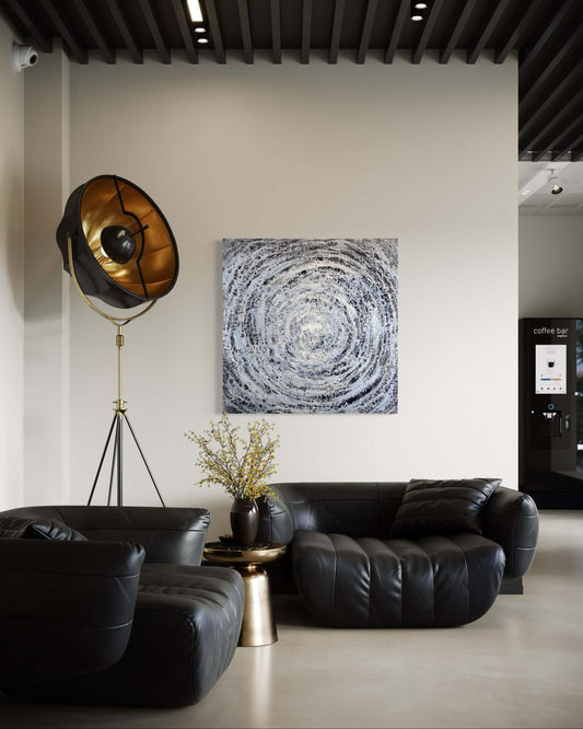 Modern living room with black leather sofas, a gold floor lamp, and abstract wall art.
