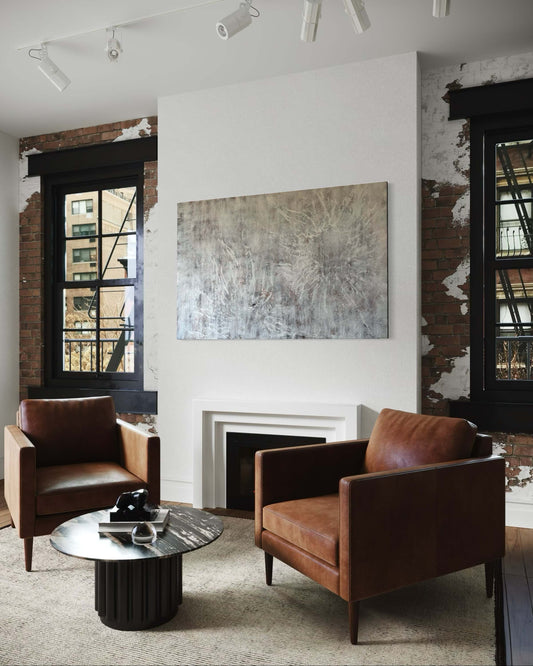 In a modern loft, above the fireplace.Abstract painting featuring soft, layered textures in pale neutral tones of white, beige, and hints of brown. Translucent, web-like veining spreads across the surface, creating a sense of mist, depth, and organic movement reminiscent of fog or frost.