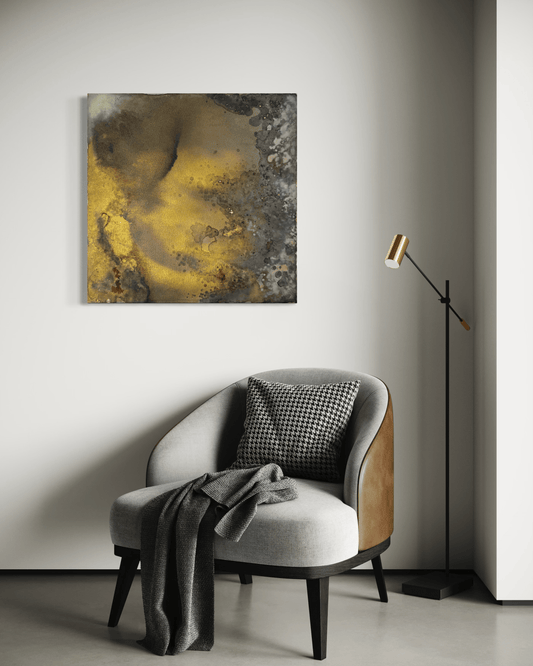 Original abstract painting with brown, rust, gold and grey tones with layered textures and organic forms displayed above an armchair and floor lamp in modern interior