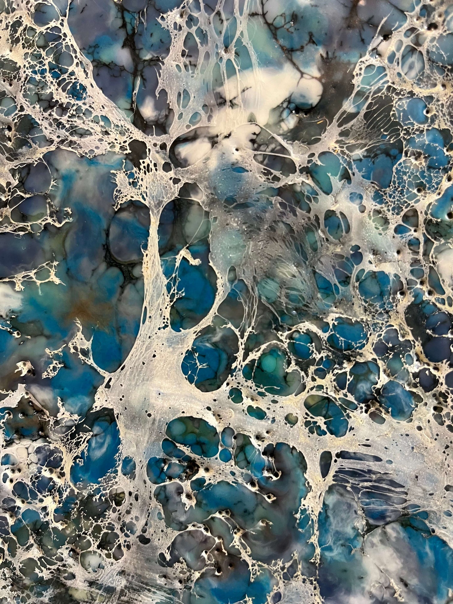 Close up.Encaustic painting in blue and white tones with lots of visual texture and many lace-like swirls. Square panel 40x40inches. It is an abstract painting, and it resembles foaming ocean waters as they hit the rocks.