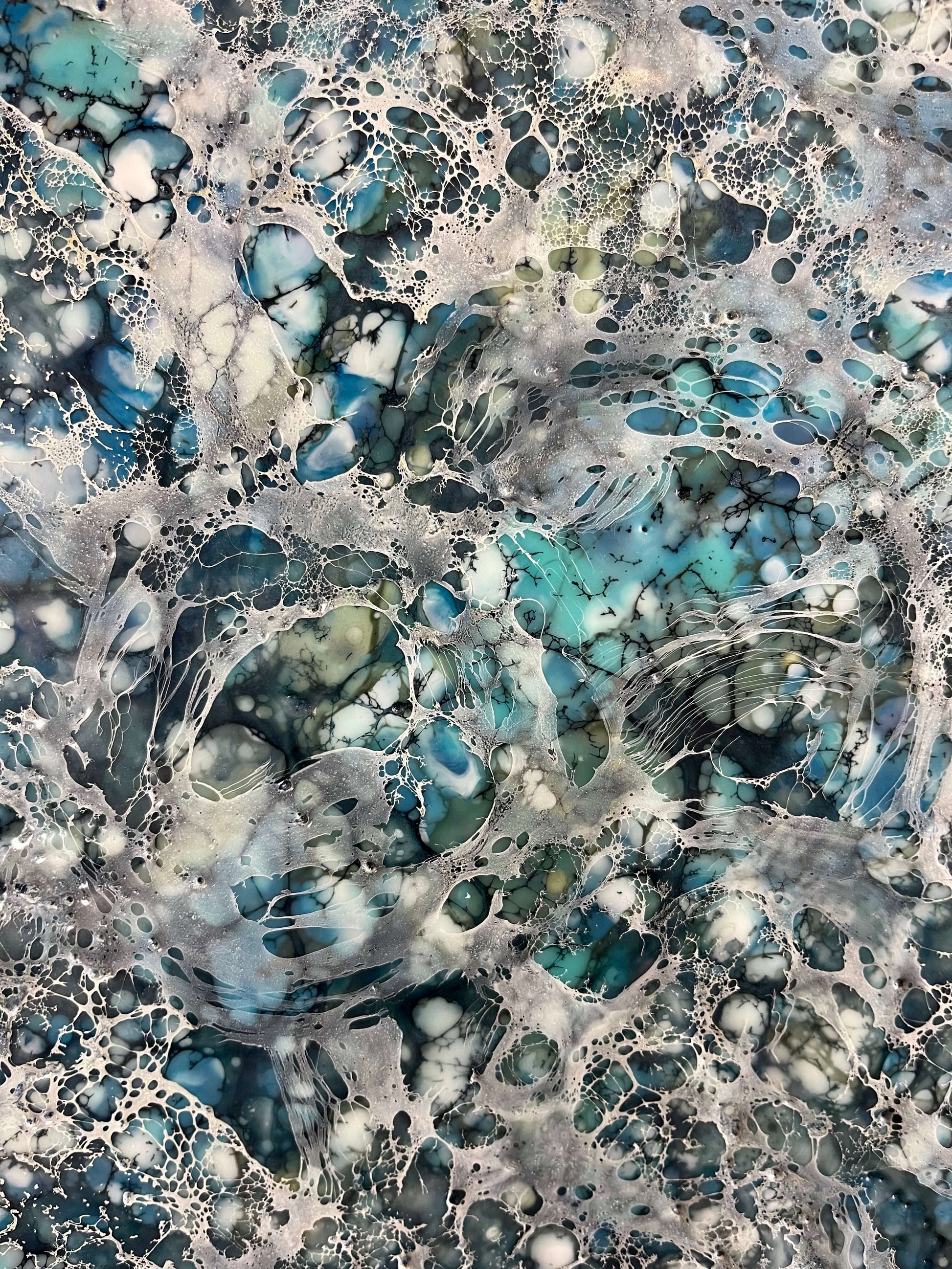 Close up.Encaustic painting in blue and white tones with lots of visual texture and many lace-like swirls. Square panel 40x40inches. It is an abstract painting, and it resembles foaming ocean waters as they hit the rocks.