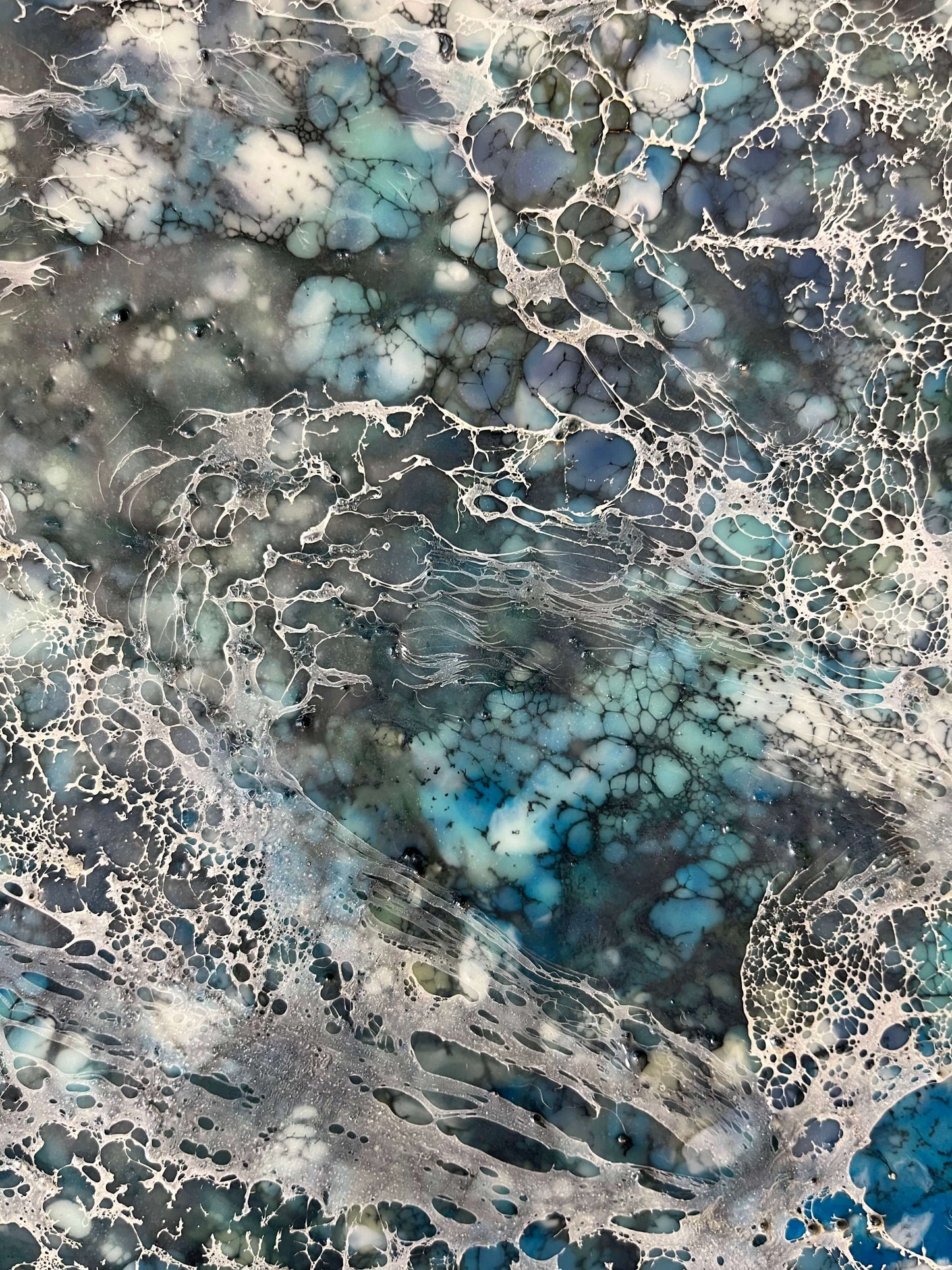 Close up.Encaustic painting in blue and white tones with lots of visual texture and many lace-like swirls. Square panel 40x40inches. It is an abstract painting, and it resembles foaming ocean waters as they hit the rocks.