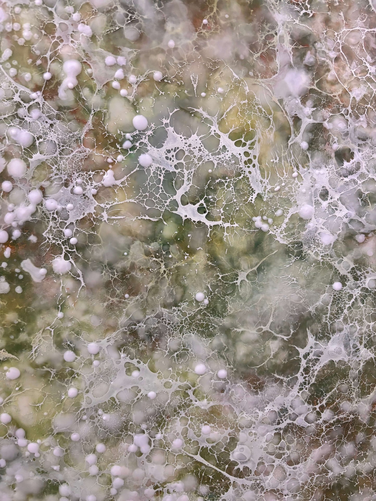 Close up.Abstract painting with delicate layers of soft white, mossy green and earthy tones. The surface is textured with fine, mist like dots, and organic forms, evoking a sense of gentle movement, growth, and natural stillness. 