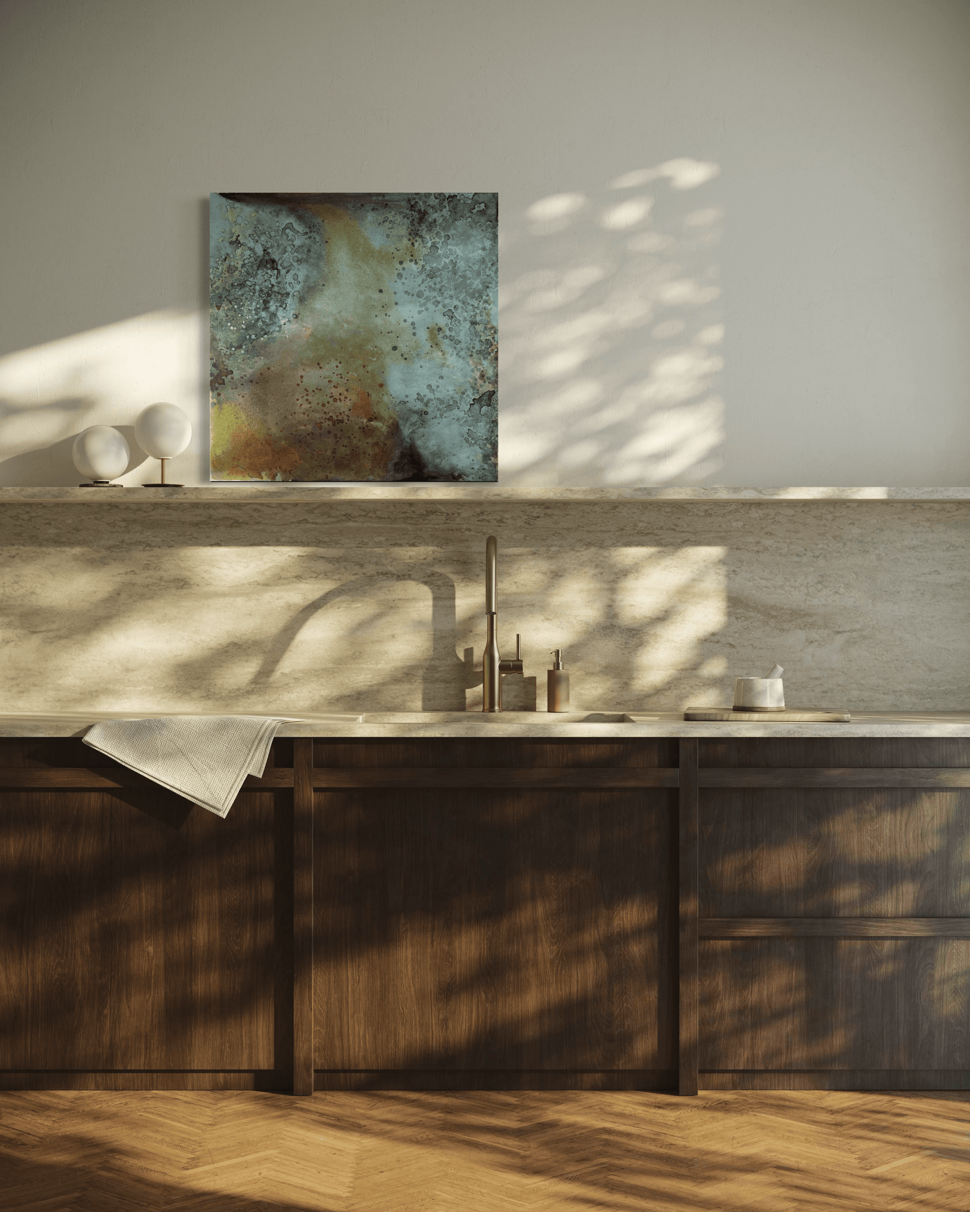 Original abstract painting in blue, grey, brown and gold tones with layered textures and organic forms displayed on a stone shelf/backsplash  in a modern kitchen interior. 