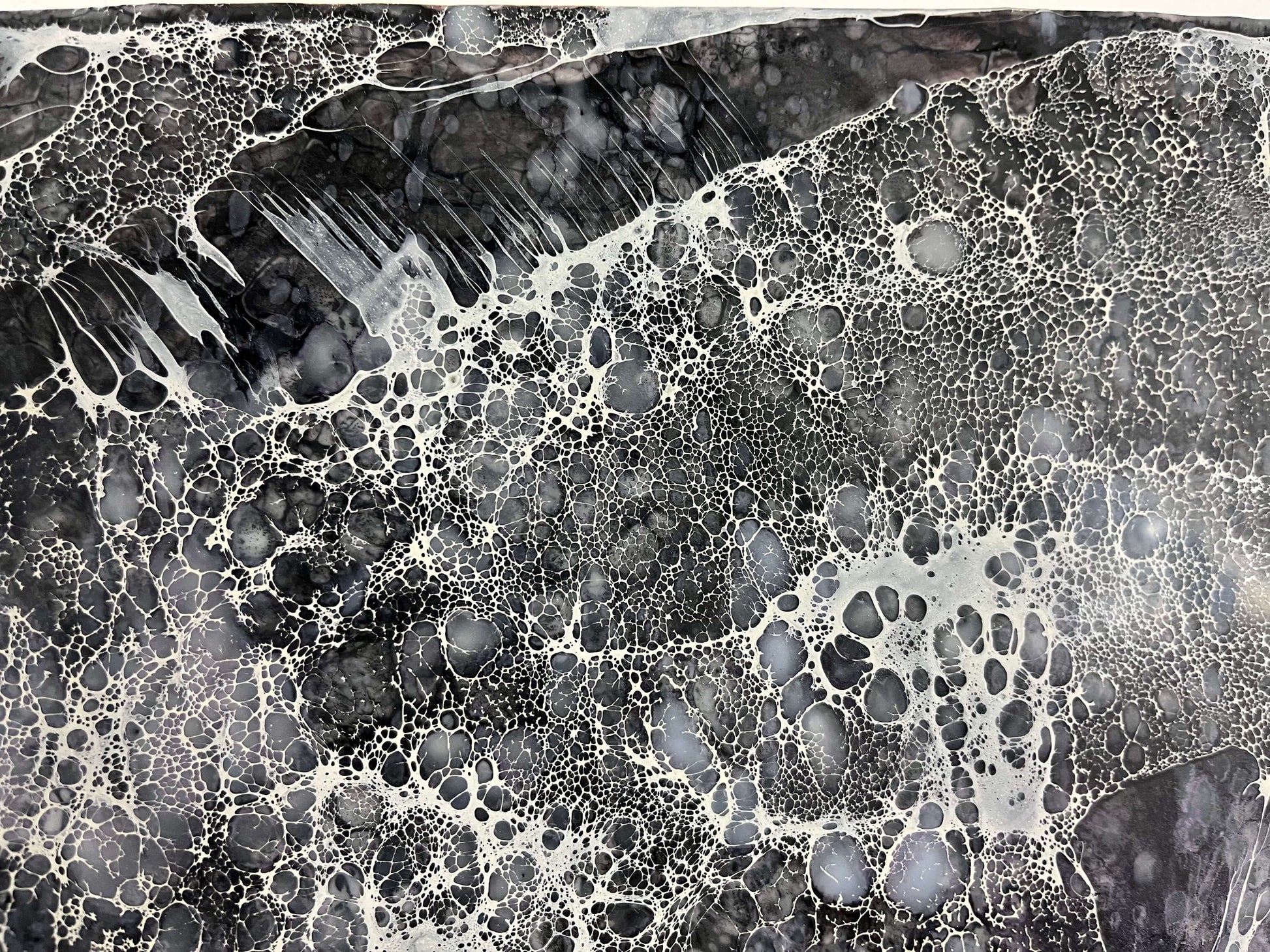 Close up.Abstract Encaustic Painting, 30x40in. Created with beeswax, damar resin, dry pigments and shellac on cradled wood panel. This piece is very striking, it is monochromatic painted in colours varying from black, grey and white. Shellac lace-like cells are burned in a direction that creates movement across the painting. Hanging hardware is included